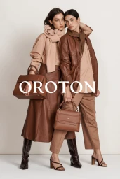 Two female models wearing layered brown and tan apparel and holding leather handbags against a plain studio background.