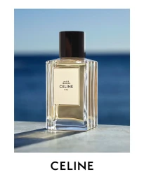 Celine Un Été Français perfume bottle on a stone surface overlooking the blue sea under bright sunlight.