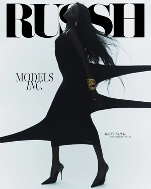 Model in a black dress with dramatic stretching fabric against a white backdrop for a Russh magazine cover by Tim Ashton.