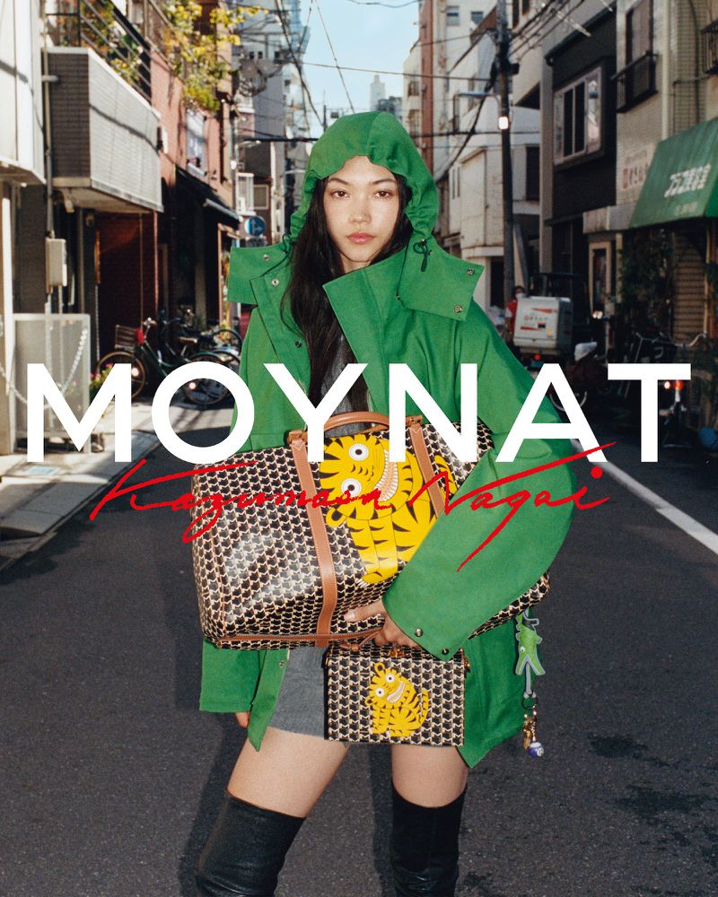 Asian woman in an urban street wearing a green hooded jacket and knee-high boots, carrying logoed bags with cartoon tiger illustration.