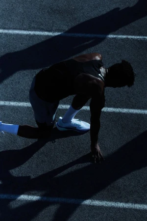 Athlete in starting position on running track, silhouetted against bright lane lines, showcasing determination and focus in fitness and sport.