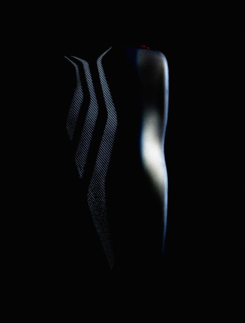 Sleek, dark athletic shirt with subtle texture and reflective design elements, set against a deep black background in a studio setting.