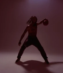 Derrick Rose dribbling a basketball in a moody red-lit studio for Fear of God Athletics