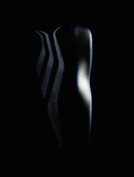 Low-key detail of a black Fear of God Athletics x Derrick Rose II basketball shoe emerging from darkness.