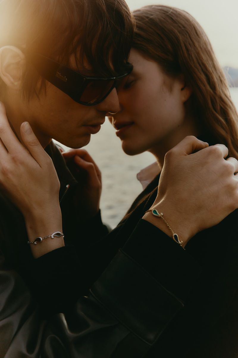 Close-up of a stylish young couple in sunglasses embracing outdoors, showcasing luxury bracelets. Fashion advertisement.