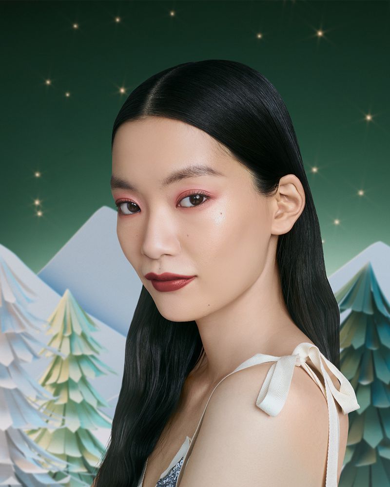 Asian woman's beauty shot set against a wintery backdrop with soft lighting showcasing makeup and skincare for beauty advertising.