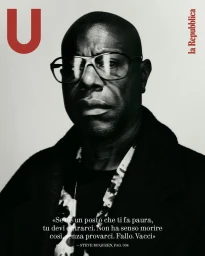 Portrait of Steve McQueen wearing large eyeglasses and a dark jacket in a monochrome photograph for U Repubblica