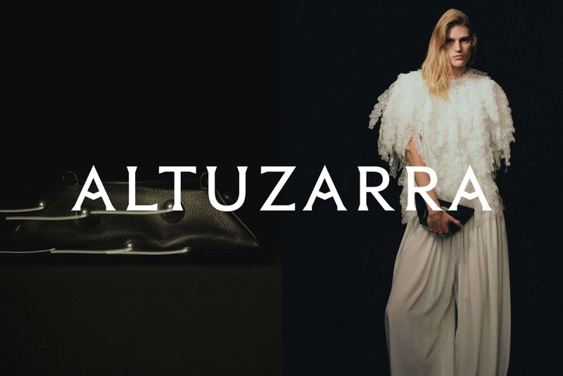 Fashion-forward studio shot: a model in a white outfit complements a black handbag, set against a sleek black background for Altuzarra.