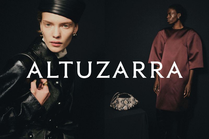 Fashion editorial shot with two women; one in a black leather jacket and hat, the other in a maroon dress, against a dark background.