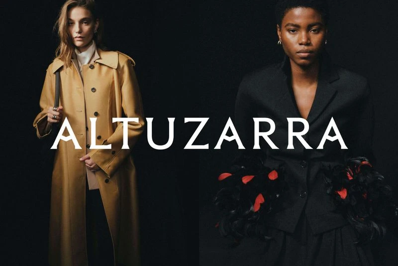 Two fashion models wearing outerwear by Altuzarra against a dark backdrop, showcasing elegant and modern styles in a studio setting.
