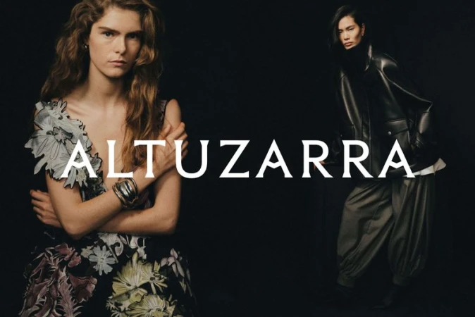 Two fashion models posing against a dark background with large white Altuzarra text overlay, wearing designer eveningwear and outerwear.