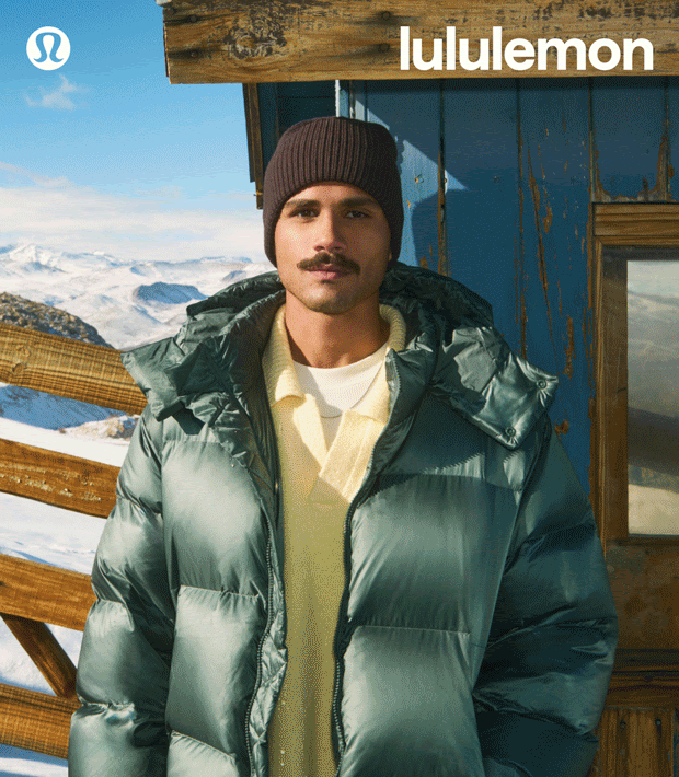 Man poses in puffer jacket with mountains visible in the background, wearing a beanie; Lululemon logo in corner.