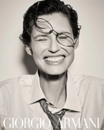 Model Bianca Balti wearing glasses on her forehead and smiling in a striped shirt for Giorgio Armani Eyewear