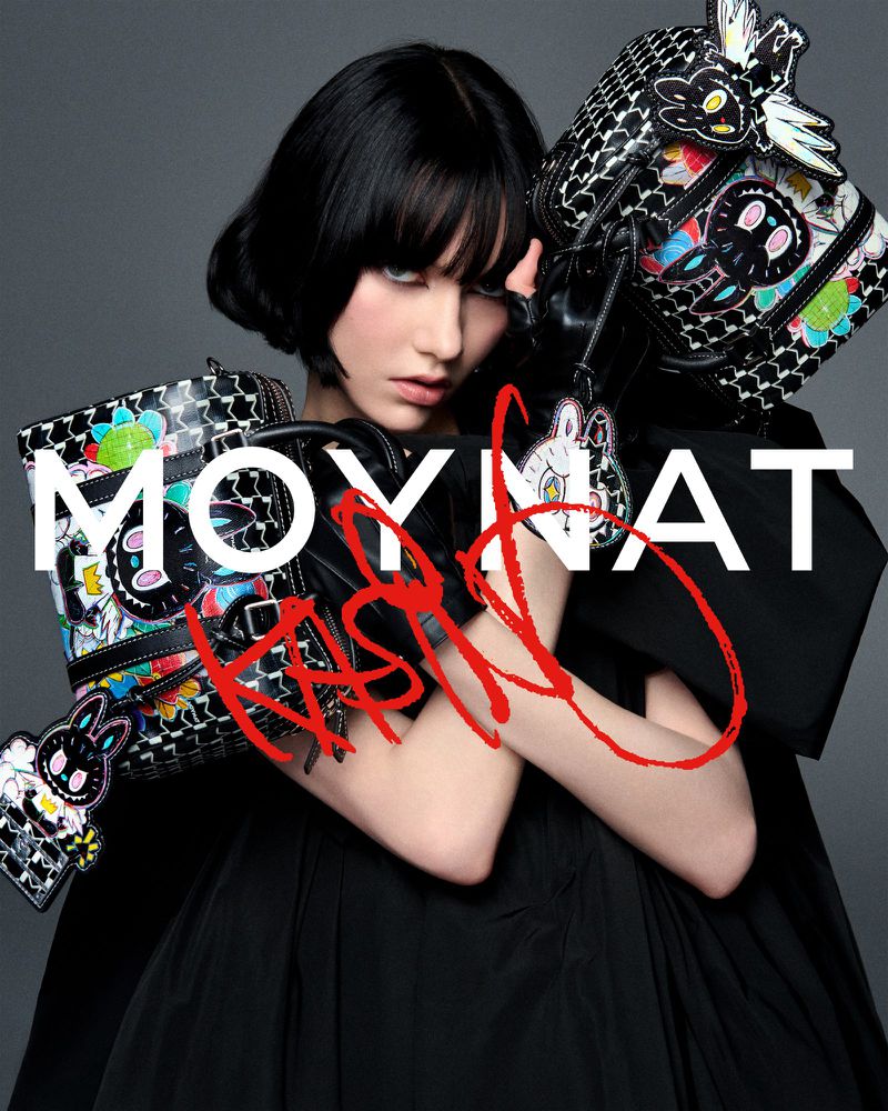 Fashion shot of a woman in a black dress holding designer handbags against a grey backdrop with prominent branding and signature overlay.