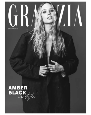 Amber Black poses in an oversized suit jacket for a black and white magazine cover, showcasing a blend of fashion and editorial style.