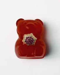 Red translucent gummy bear prop wearing a gold and ruby floral ring centered on a white seamless background.