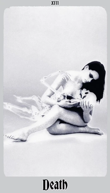Artistic grayscale image featuring a seated woman tenderly holding a skull and embracing a skeleton torso, reminiscent of tarot card imagery.