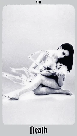 Artistic grayscale image featuring a seated woman tenderly holding a skull and embracing a skeleton torso, reminiscent of tarot card imagery.