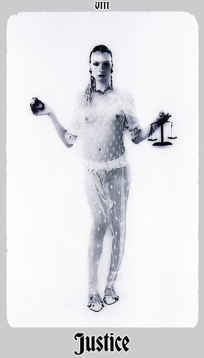 Monochromatic image of a person holding scales and an apple, evoking Justice tarot imagery, against a white backdrop.