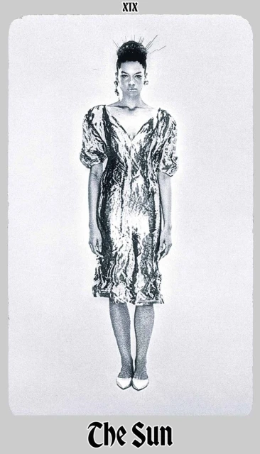 Full-length studio shot of a woman in a shimmering silver dress, with hair styled up and white shoes, against a white background.
