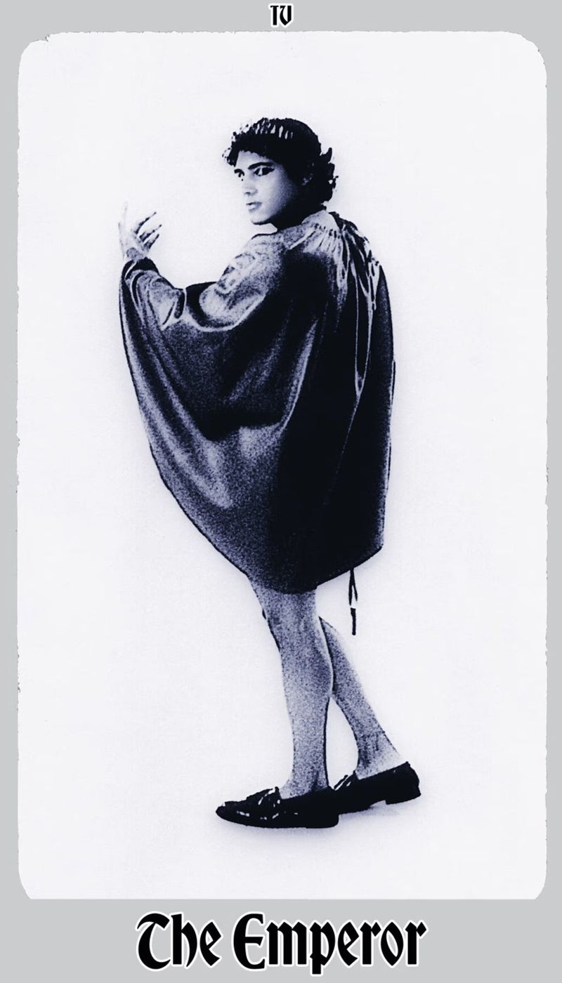 Full body shot of a male in dark tunic, pale legs, dark shoes; white gradient background; text 'The Emperor' below.