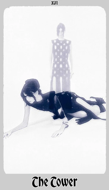 Two women strike poses in a high-fashion editorial shot with cool color grading and a clean white background, evoking a tarot card.