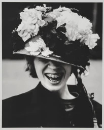 Aaron Danner laughs wearing a flower-covered helmet covering his eyes in a black and white fashion portrait.