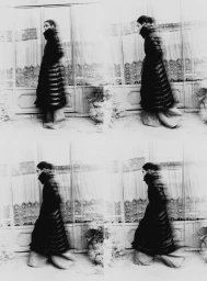 Black and white four-panel photo sequence of a model walking past window panes wearing a long quilted coat and wide trousers.