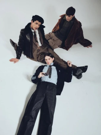 Three men in fashionable vintage-inspired outerwear lying on a white surface, showcasing retro menswear fashion with coordinated styling and design.