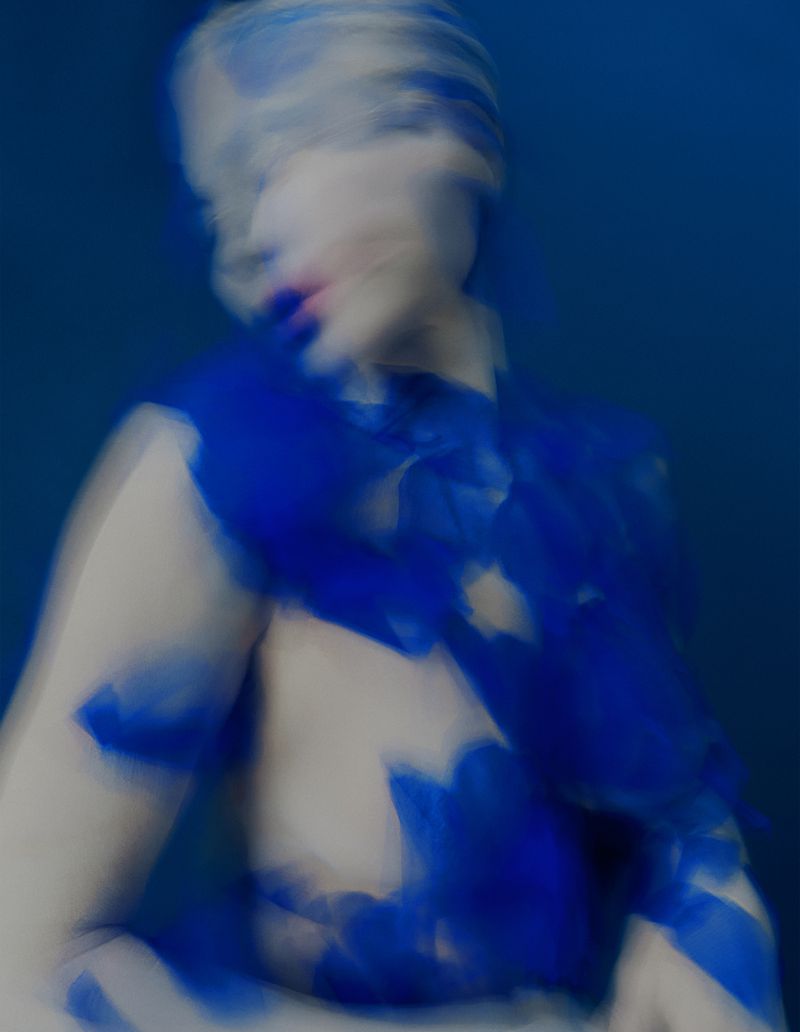 Abstract portrait with an adult woman painted with blue hues on a blue background featuring a blurred, dreamlike visual effect.
