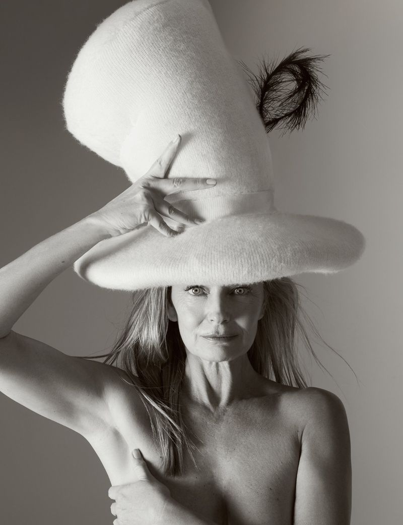 Striking black and white portrait of a woman with a unique tall hat. The hat is textured and features a dark feather accent.