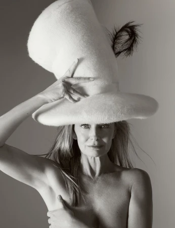 Striking black and white portrait of a woman with a unique tall hat. The hat is textured and features a dark feather accent.