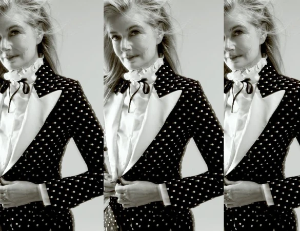 Older woman poses in polka dot blazer and white blouse against light background. Black-and-white fashion portrait.