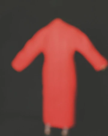 Blurred view of a person wearing a red robe, creating a hazy and indistinct image with a dark background.