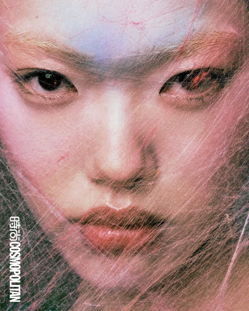 Close-up portrait of a model with light hair partially obscured by a web-like material, showcasing a beauty and fashion concept.