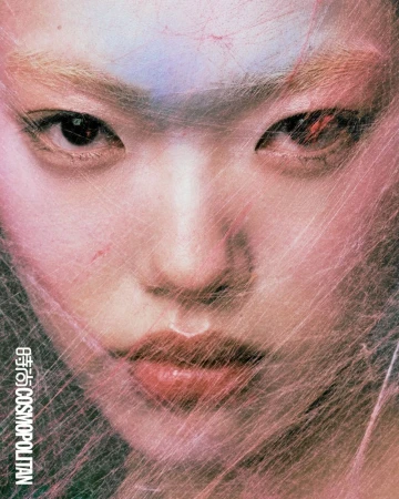 Close-up portrait of a model with light hair partially obscured by a web-like material, showcasing a beauty and fashion concept.