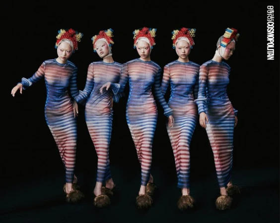 Five Asian women in striped dresses and elaborate headwear pose in a studio against a black background for a fashion editorial.