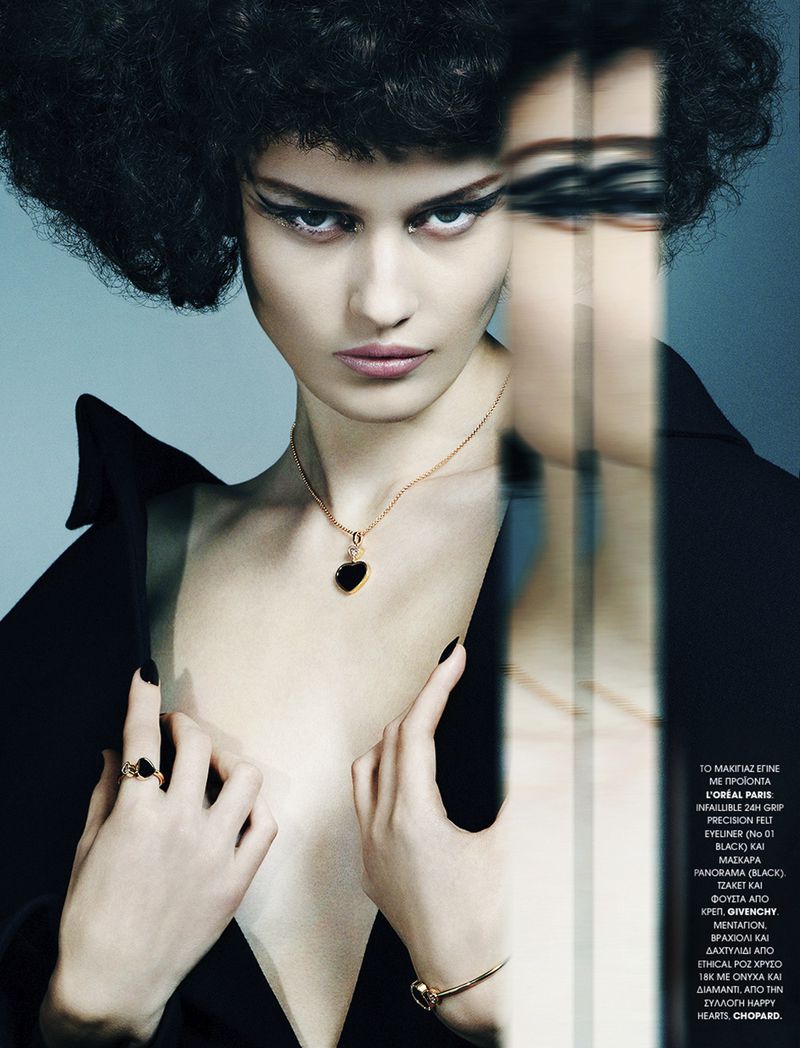 A striking studio shot shows a woman in a black jacket and dark hair, wearing a heart pendant necklace, ring, and bracelet jewelry.