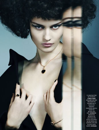 A striking studio shot shows a woman in a black jacket and dark hair, wearing a heart pendant necklace, ring, and bracelet jewelry.