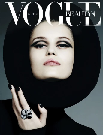 Vogue Greece cover featuring a model with strong eye makeup, a large black hat, black turtle neck top, and an ornate gemstone ring.
