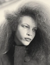 Close-up portrait of model Tianna St. Louis with voluminous textured hair wearing a dark coat for Crosswind.