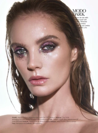 Close-up beauty shot of an adult female model with glitter makeup on her eyes and glossy lips in a bright studio setting.