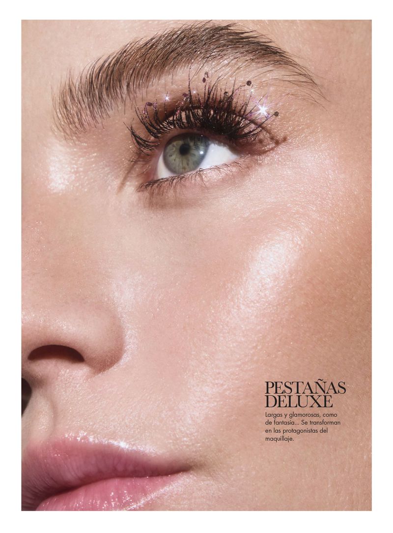 Close-up studio shot of a woman's face with makeup focusing on her eye, eyelashes, and eyebrow, with a soft, glowing complexion.