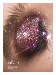 Close-up of a model's closed eye covered in shimmering magenta and purple glitter makeup with sparkling light flares.