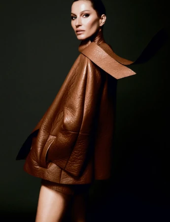 Fashion shot of a woman wearing a brown leather jacket in a studio setting with dark backdrop and dramatic lighting, side view portrait.