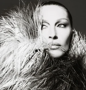 Black and white close-up portrait of Gisele Bündchen enveloped in a voluminous feathered collar looking to the side.