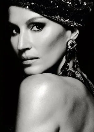 Black and white portrait of Gisele Bündchen looking over her shoulder wearing a sequined headpiece and statement drop earring.