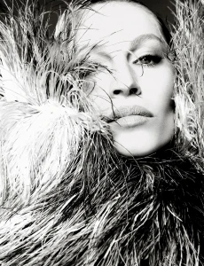 Black and white close-up portrait of Gisele Bündchen framed by a voluminous textured feather collar.