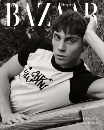 Black and white portrait of a young man lying on wooden planks in front of foliage, fashion editorial for Harper's Bazaar Vietnam.