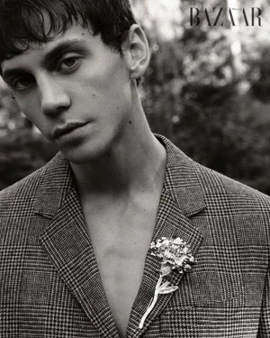 Black and white portrait of Matteo Miccini wearing a plaid blazer with a floral brooch for Harper's Bazaar Vietnam.